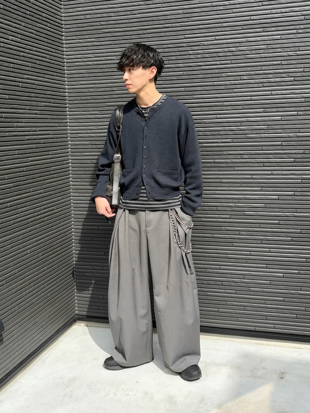 ブラック系のTシャツ/カットソー、ブラック系のカーディガン/ボレロ、グレー系のスラックスを着用したメンズの春コーディネートの3枚目の写真