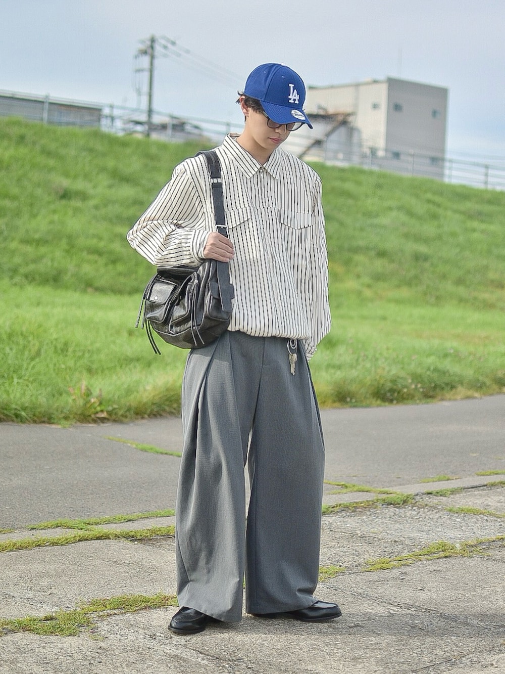 ホワイト系のブルゾン、グレー系のスラックス、ブラック系のショルダーバッグを着用したメンズの秋コーディネートの2枚目の写真