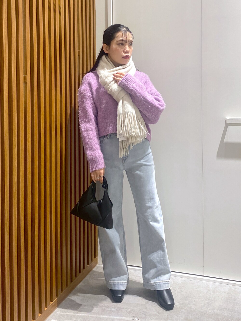 パープル系のニット/セーター、ブラック系のショルダーバッグ、ブルー系のデニムパンツを着用したレディースの冬コーディネートの2枚目の写真