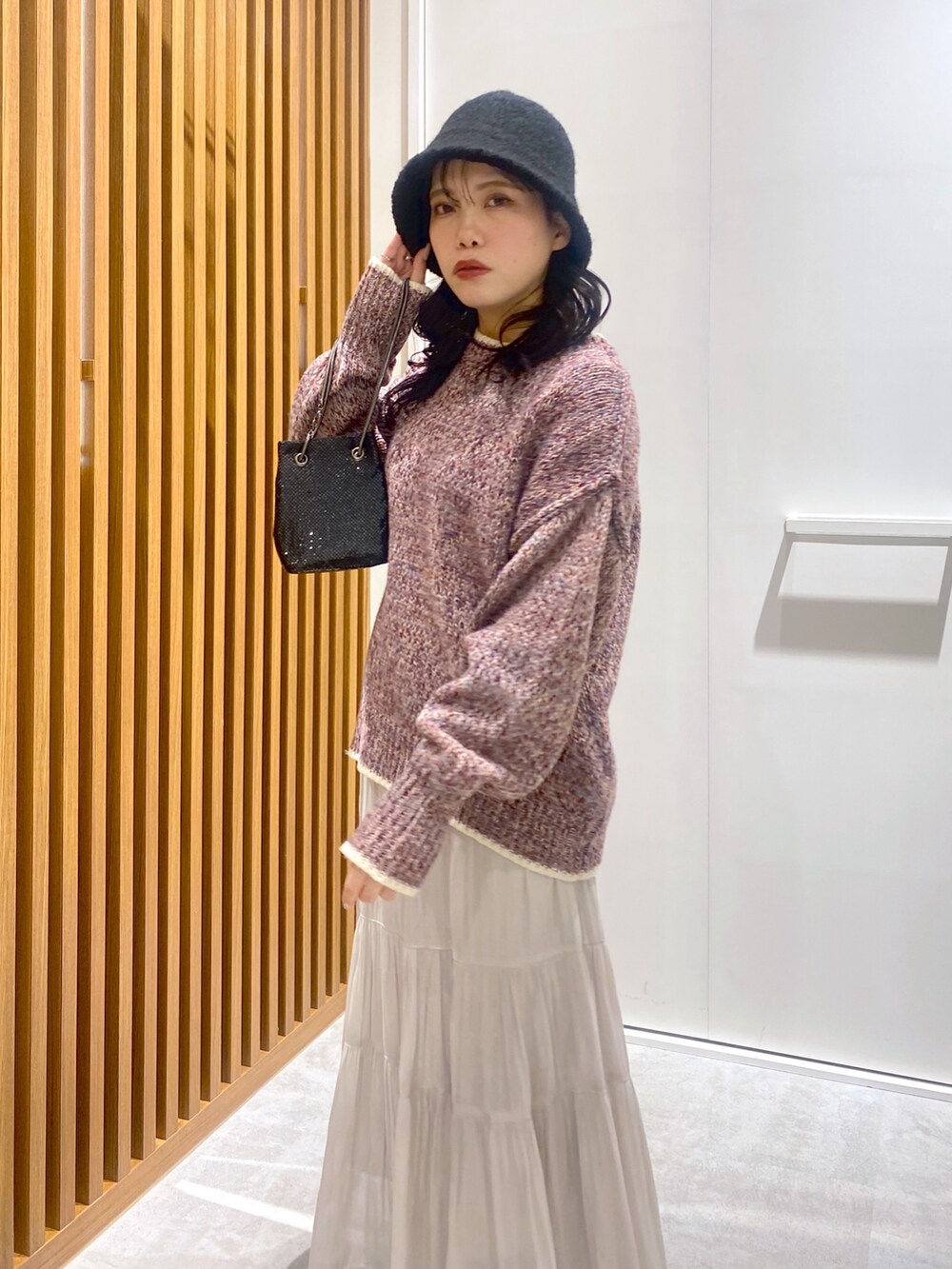 レッド系のニット/セーター、ホワイト系のスカート、ブラック系のショルダーバッグを着用したレディースの冬コーディネートの3枚目の写真