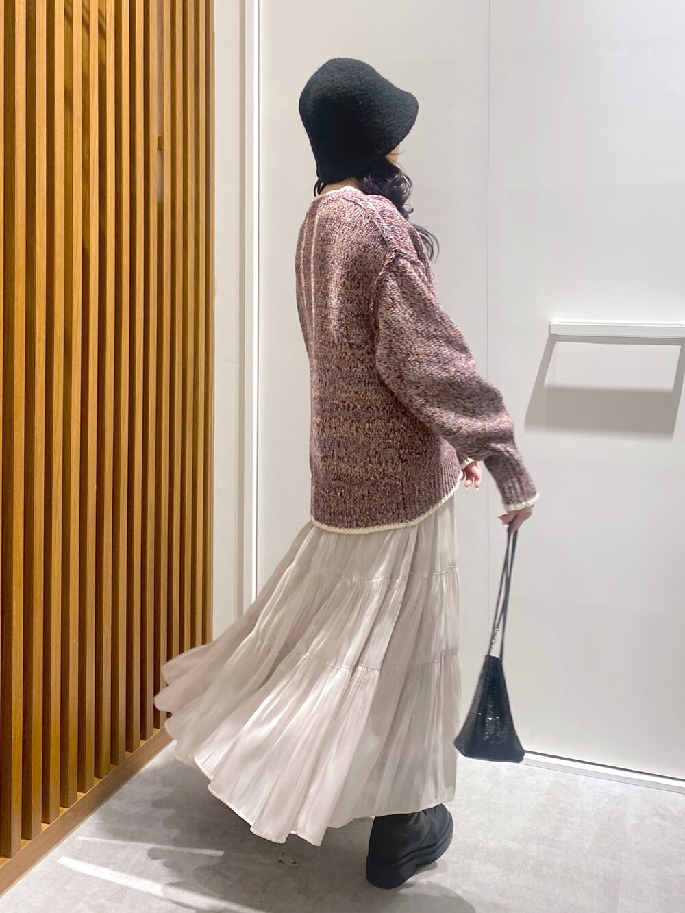 レッド系のニット/セーター、ホワイト系のスカート、ブラック系のショルダーバッグを着用したレディースの冬コーディネートの2枚目の写真