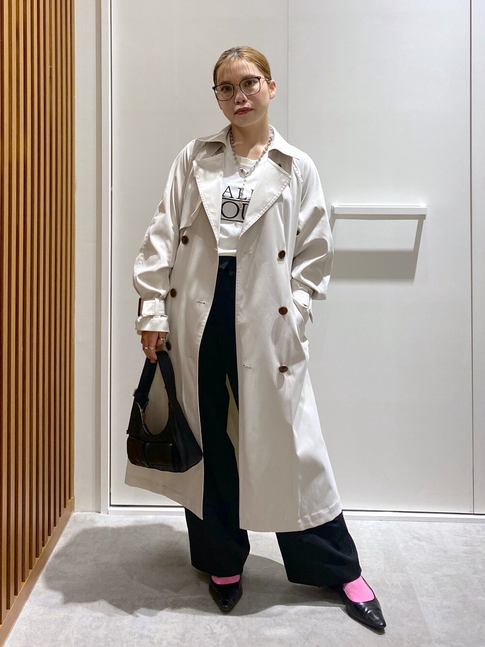 ホワイト系のTシャツ/カットソー、ホワイト系のトレンチコート、ブラック系のショルダーバッグを着用したレディースの春コーディネートの2枚目の写真