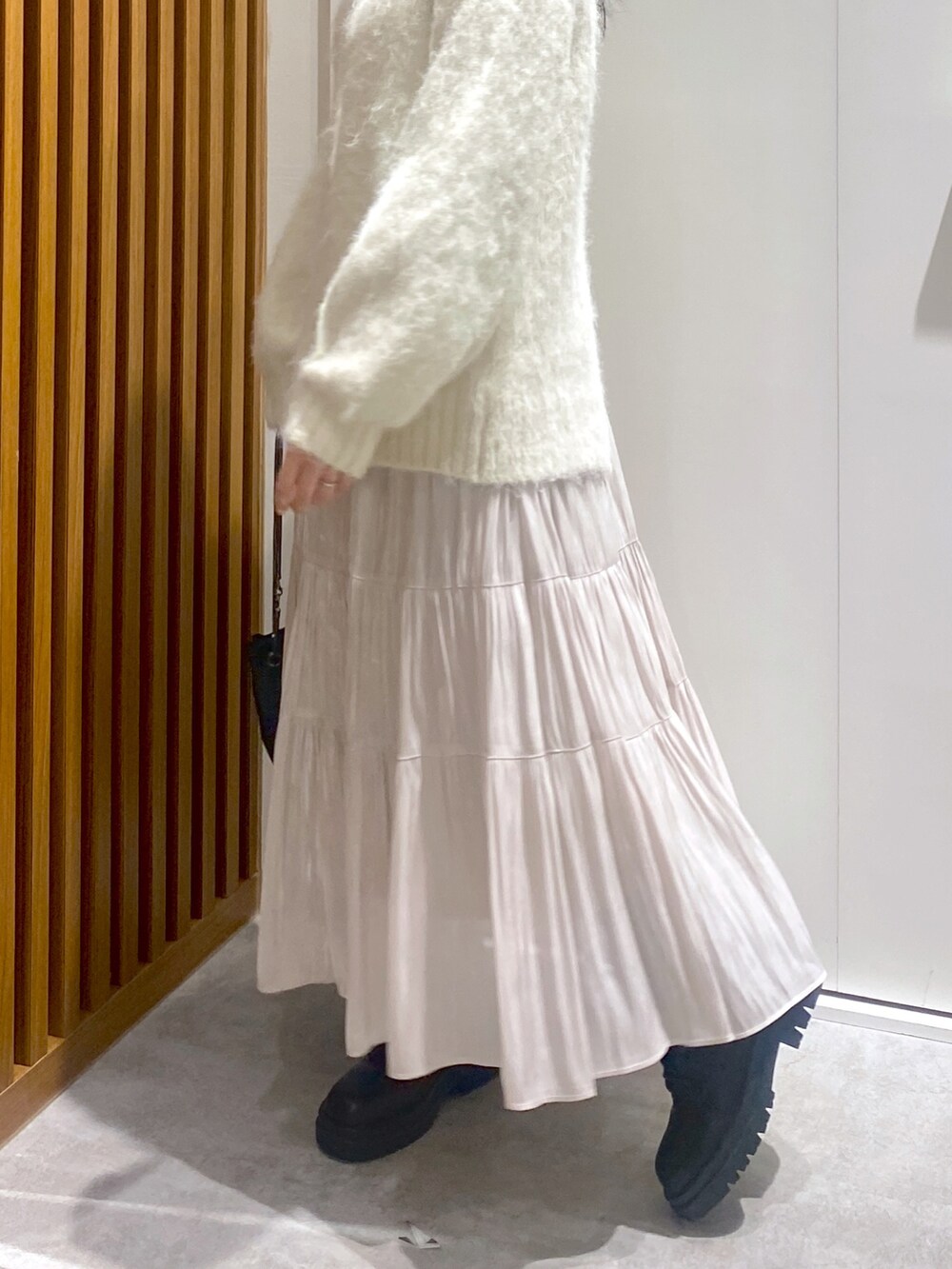 ホワイト系のニット/セーター、ブラック系のショルダーバッグ、ホワイト系のスカートを着用したレディースの冬コーディネートの4枚目の写真