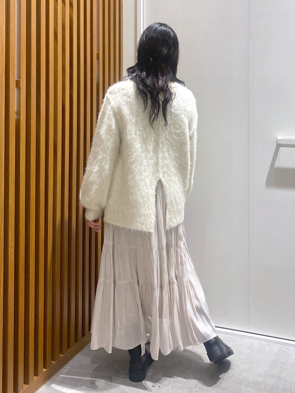 ホワイト系のニット/セーター、ブラック系のショルダーバッグ、ホワイト系のスカートを着用したレディースの冬コーディネートの3枚目の写真