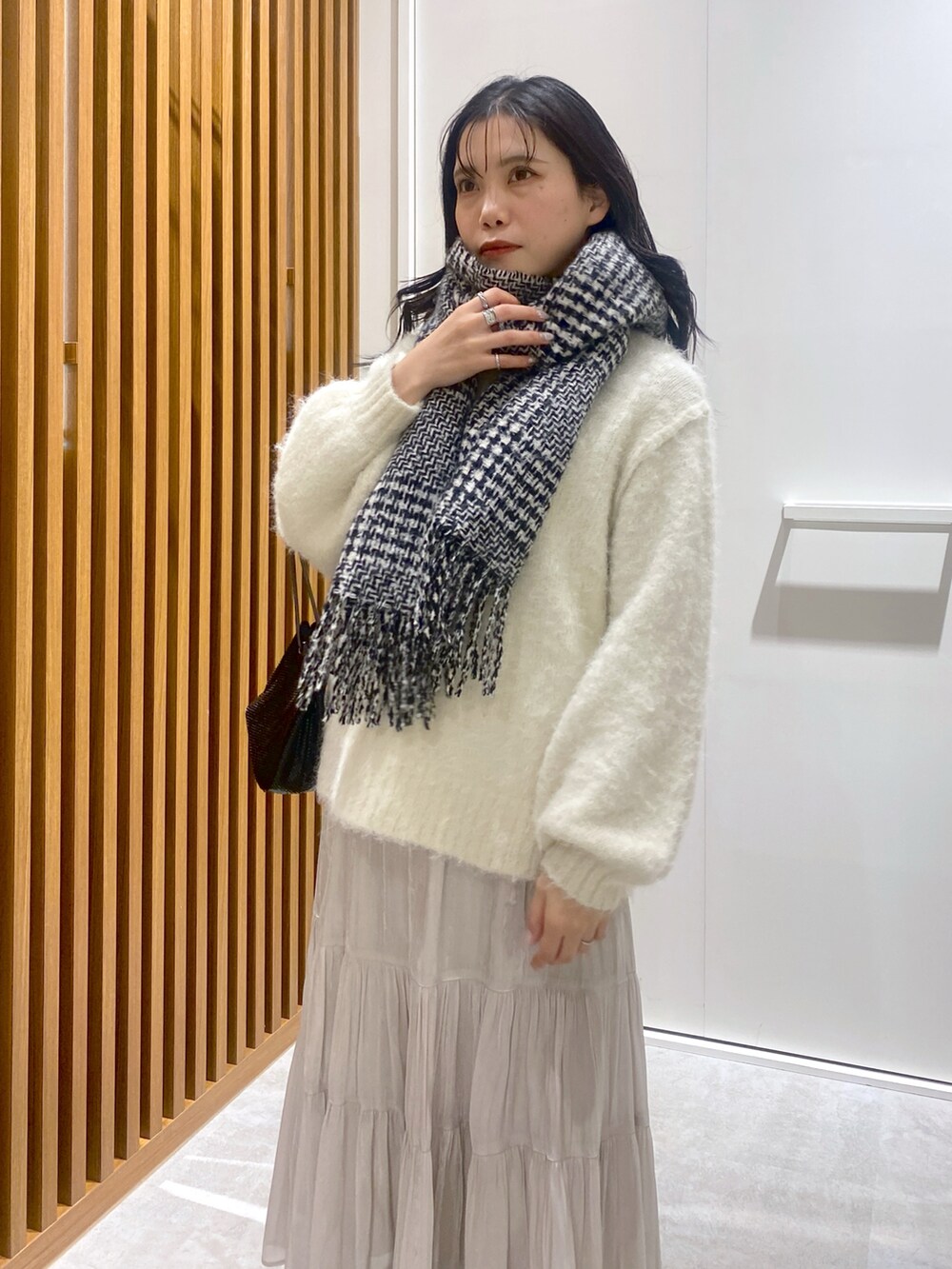 ホワイト系のニット/セーター、ブラック系のショルダーバッグ、ホワイト系のスカートを着用したレディースの冬コーディネートの5枚目の写真