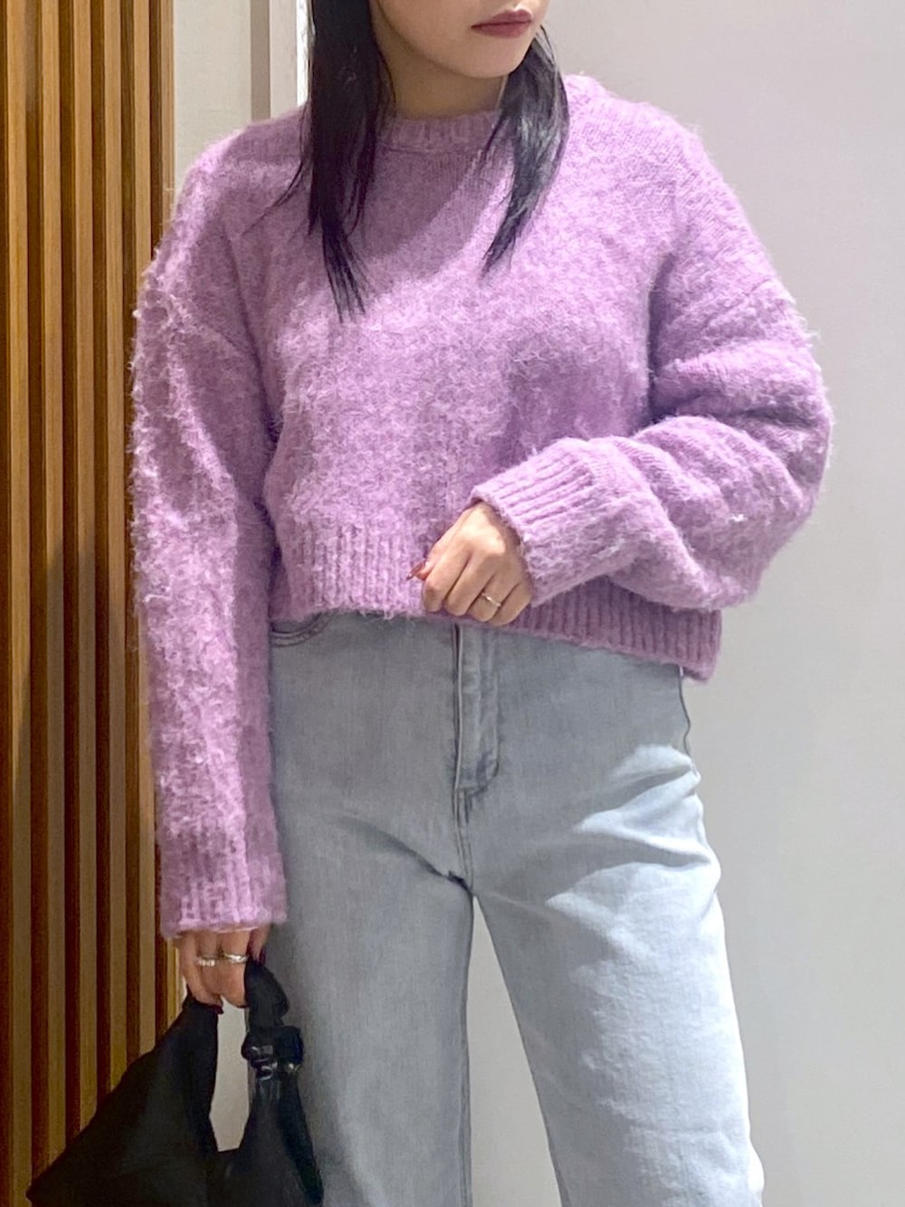 パープル系のニット/セーター、ブラック系のショルダーバッグ、ブルー系のデニムパンツを着用したレディースの冬コーディネートの3枚目の写真