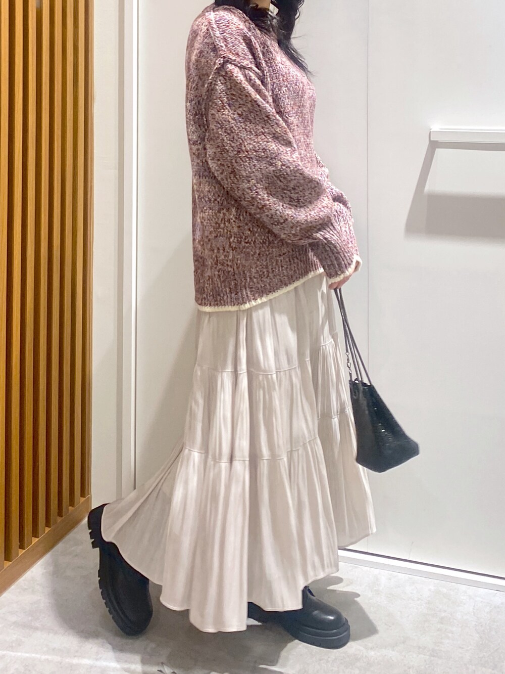 レッド系のニット/セーター、ホワイト系のスカート、ブラック系のショルダーバッグを着用したレディースの冬コーディネートの4枚目の写真