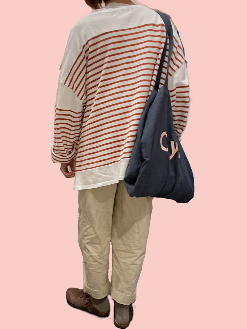 グレー系のトートバッグ、オレンジ系のTシャツ/カットソー、ブラウン系のサンダルを着用したレディースの秋コーディネートの3枚目の写真