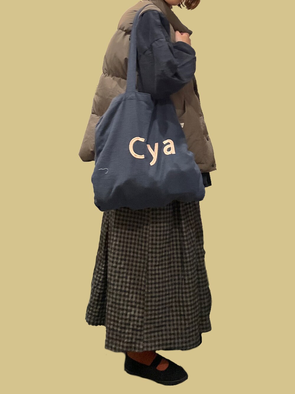 グレー系のトートバッグ、グレー系のシャツ/ブラウス、ベージュ系のダウンベストを着用したレディースの冬コーディネートの3枚目の写真