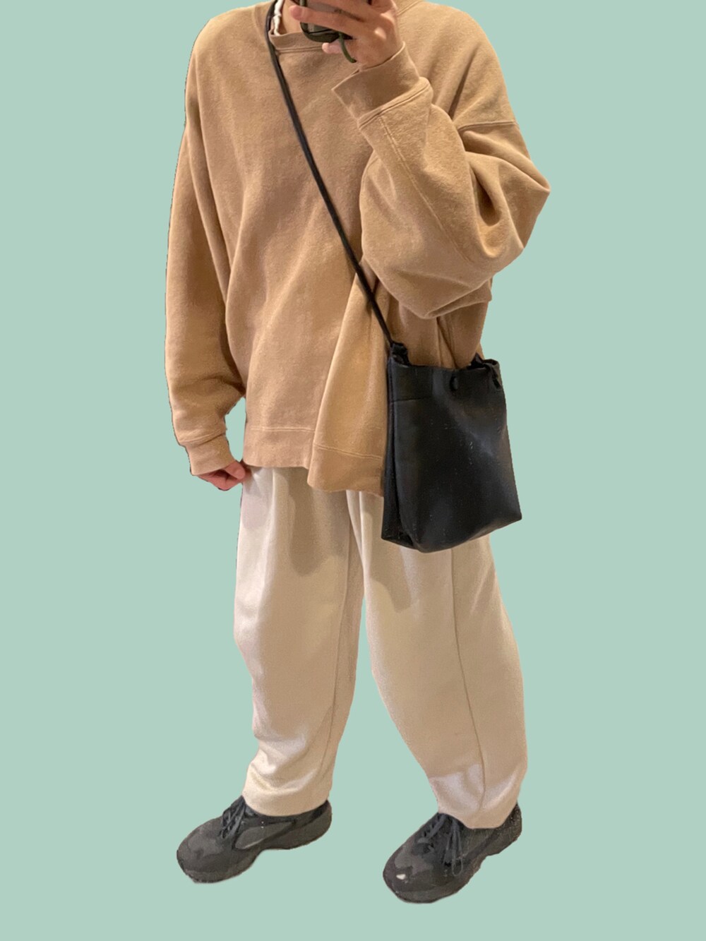 ベージュ系のスウェット、ブラック系のショルダーバッグ、ブラック系のスニーカーを着用したレディースの冬コーディネートの2枚目の写真