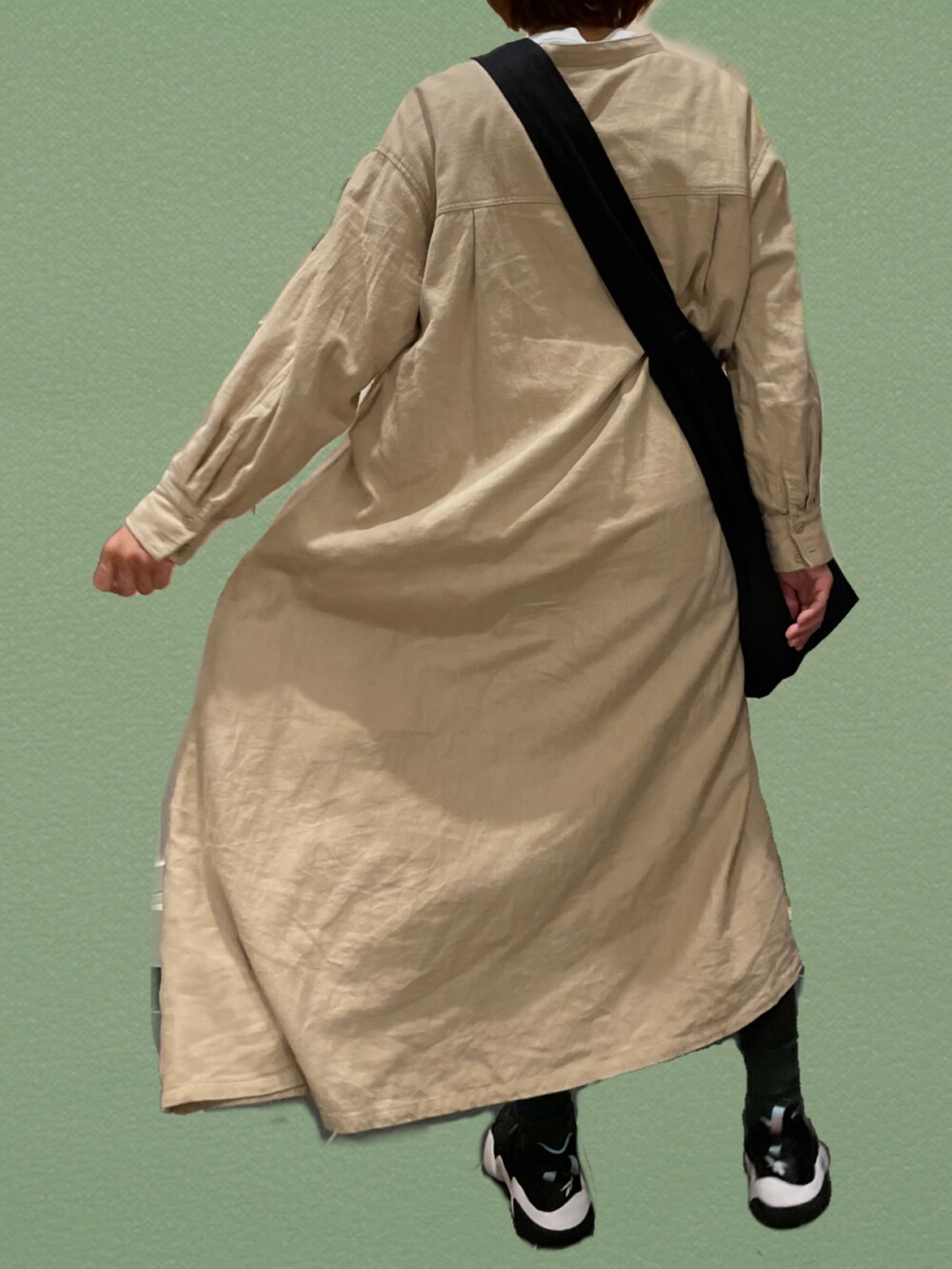 ブラック系のショルダーバッグ、ベージュ系のワンピース、ブラック系のスニーカーを着用したレディースの秋コーディネートの2枚目の写真