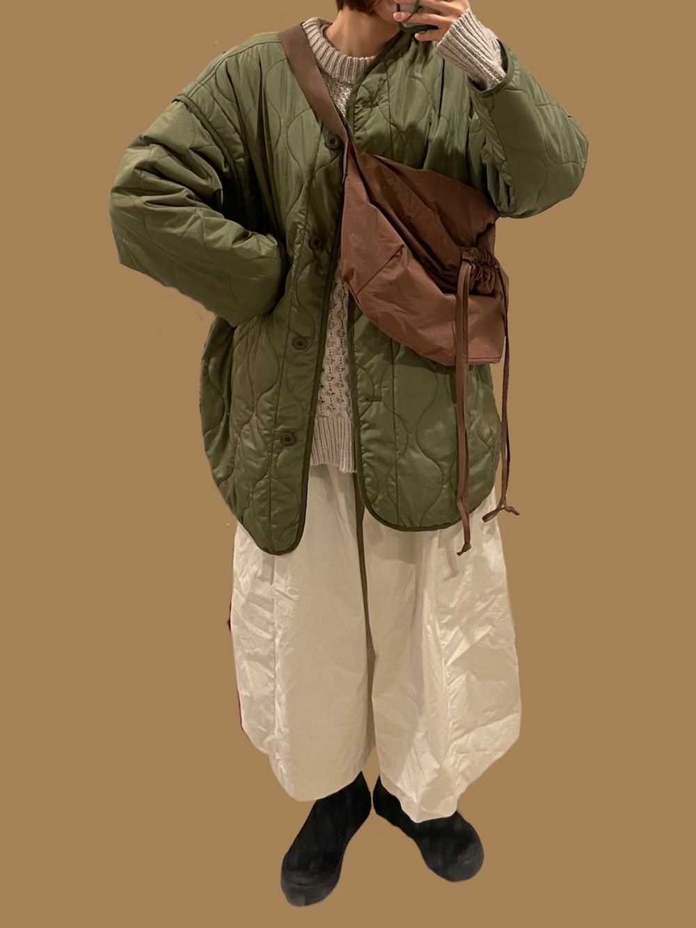 ブラック系のブーツ、ホワイト系のスカート、ベージュ系のニット/セーターを着用したレディースの冬コーディネートの2枚目の写真