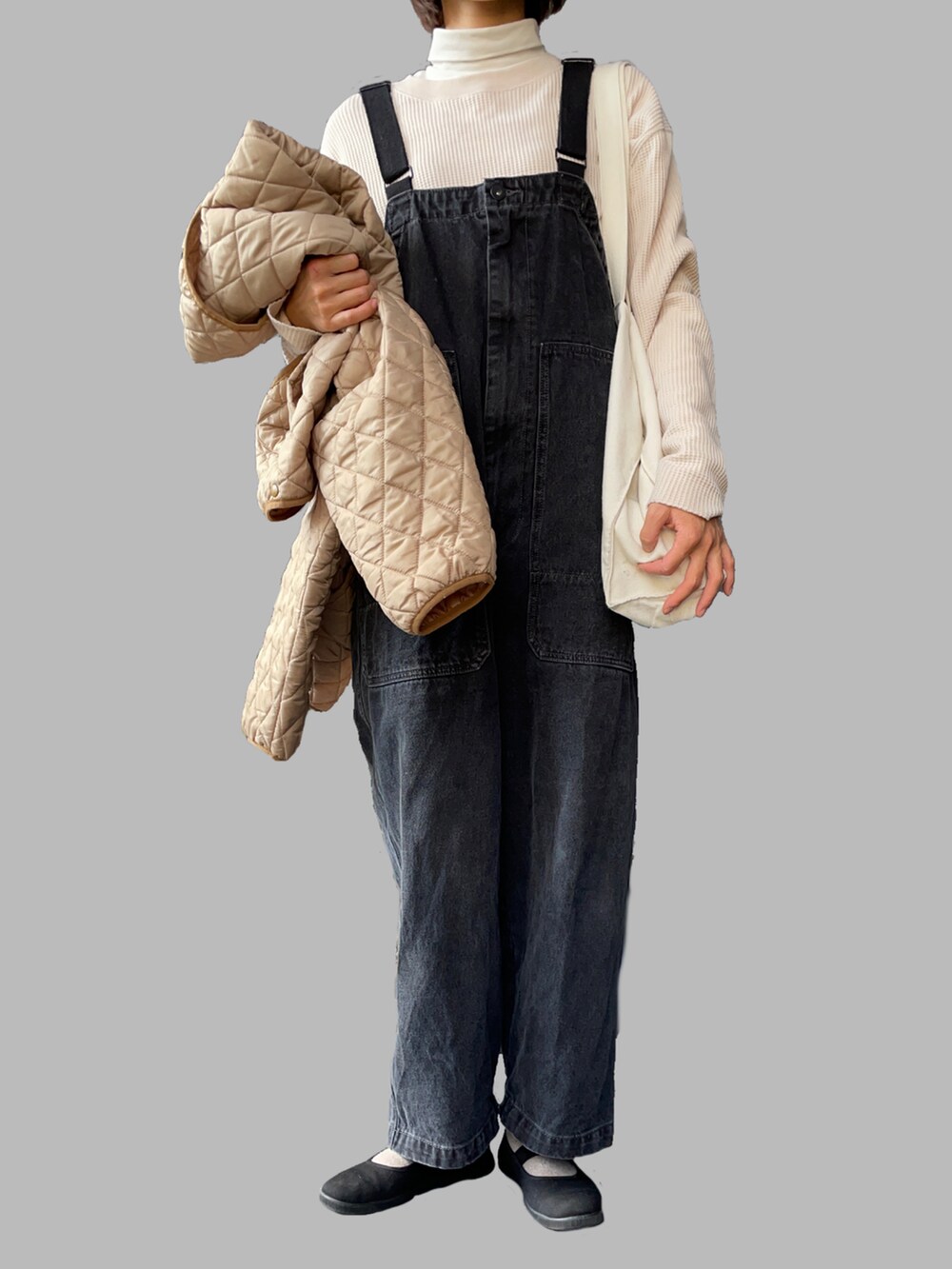 ベージュ系のブルゾン、ブラック系のサロペット/オーバーオール、ブラック系のスニーカーを着用したレディースの冬コーディネートの2枚目の写真