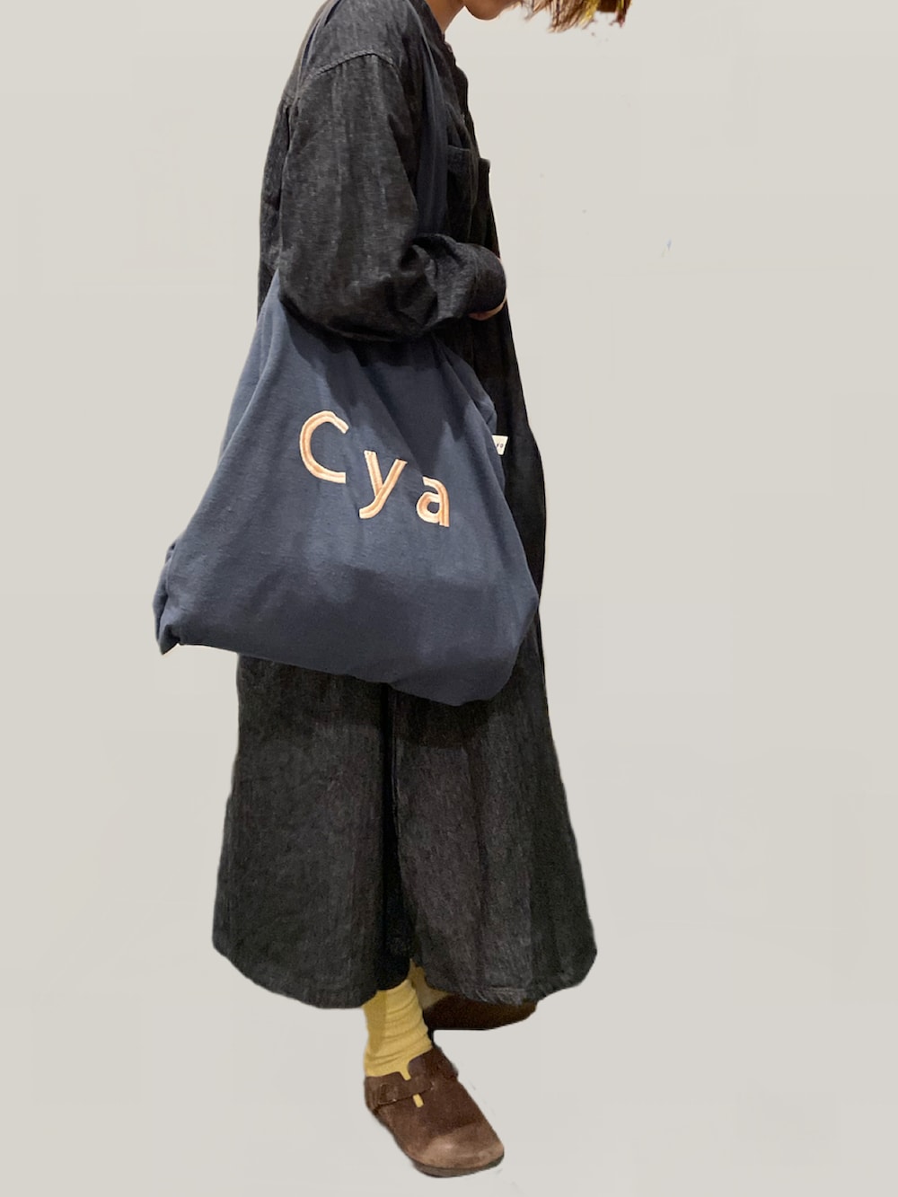 ブラウン系のスニーカー、グレー系のトートバッグ、ブラック系のワンピースを着用したレディースの秋コーディネートの3枚目の写真