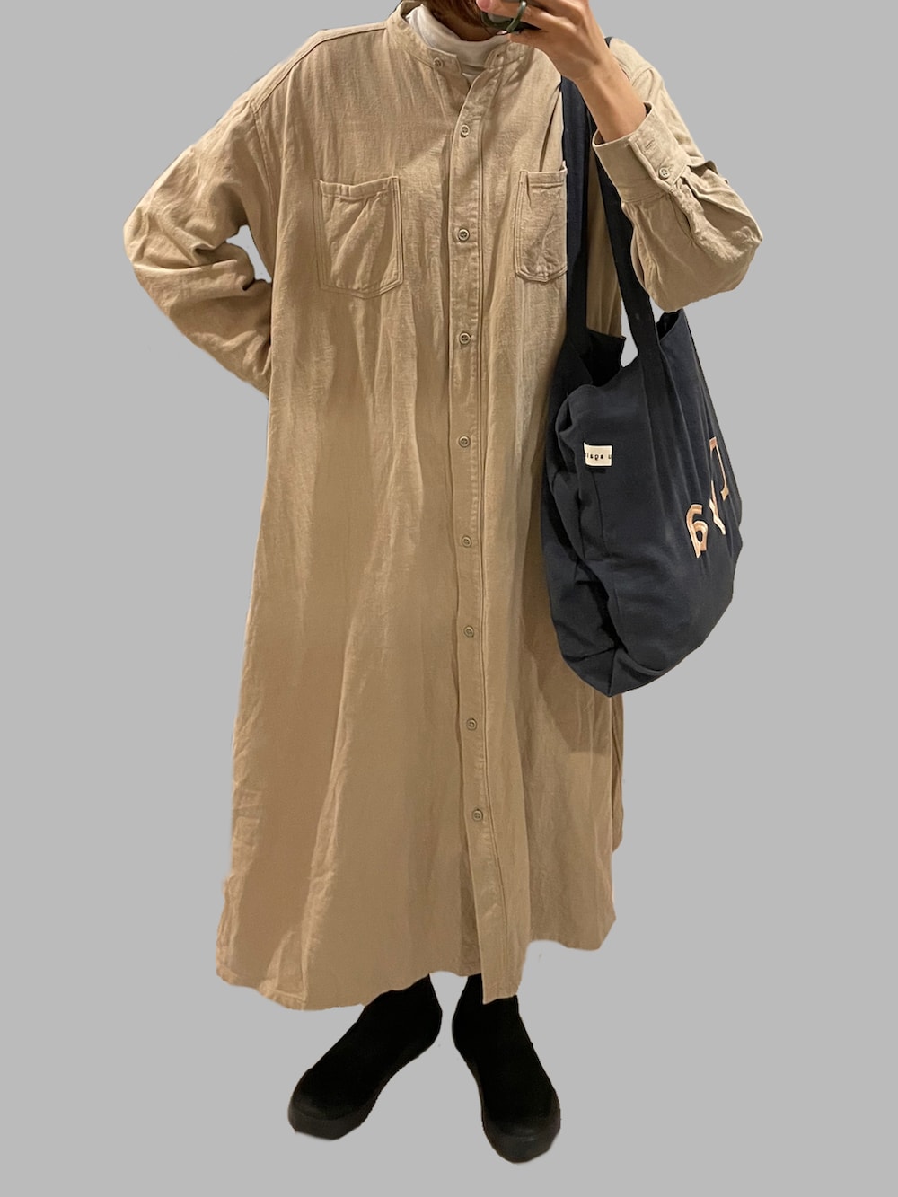 ベージュ系のブルゾン、ベージュ系のワンピース、ブラック系のブーツを着用したレディースの冬コーディネートの2枚目の写真