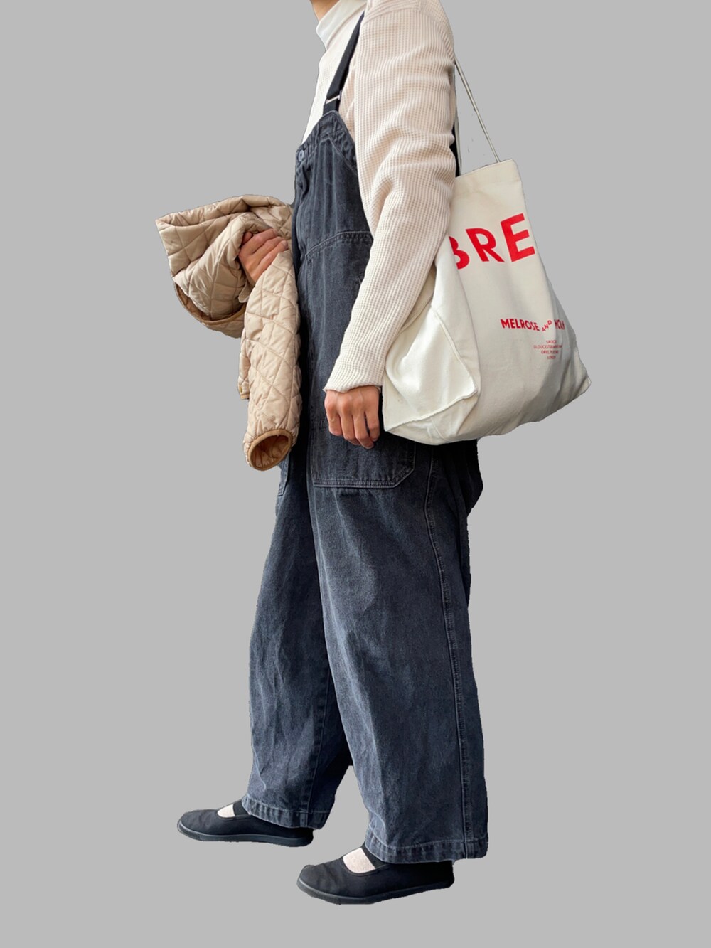 ベージュ系のブルゾン、ブラック系のサロペット/オーバーオール、ブラック系のスニーカーを着用したレディースの冬コーディネートの3枚目の写真