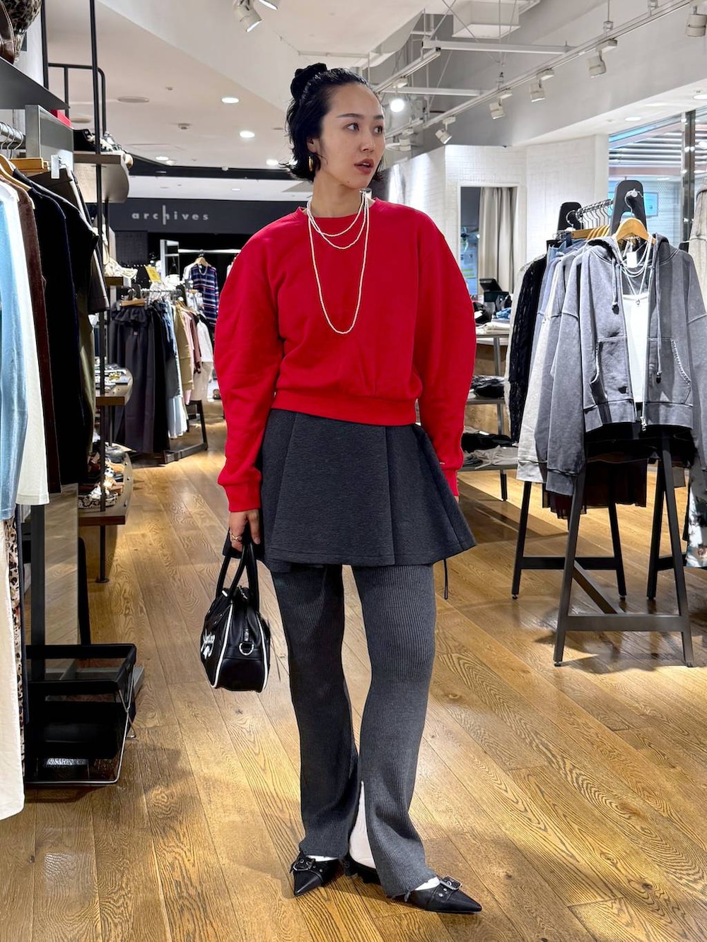 ブラック系のパンプス、ホワイト系のショルダーバッグ、グレー系のその他パンツを着用したレディースの秋コーディネートの2枚目の写真