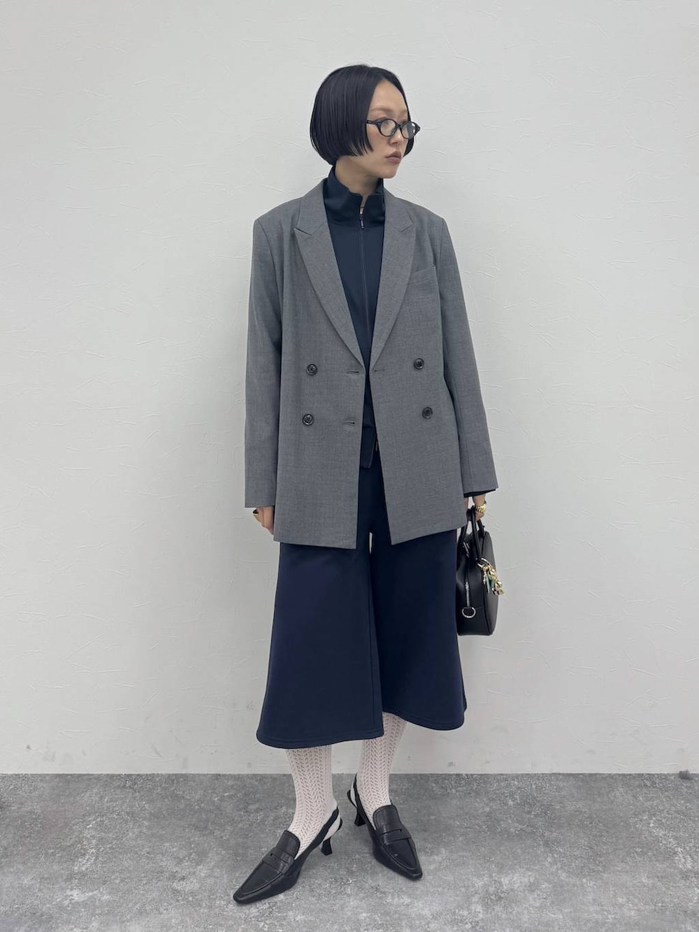 ブラック系のローファー、ブラック系のショルダーバッグ、グレー系のテーラードジャケットを着用したレディースの冬コーディネートの2枚目の写真