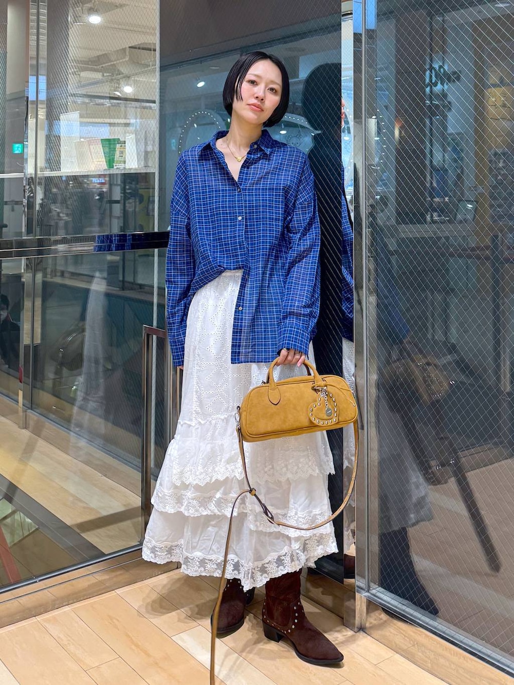 ブラウン系のボストンバッグ、ブラウン系のブーツ、ホワイト系のスカートを着用したレディースの春コーディネートの4枚目の写真