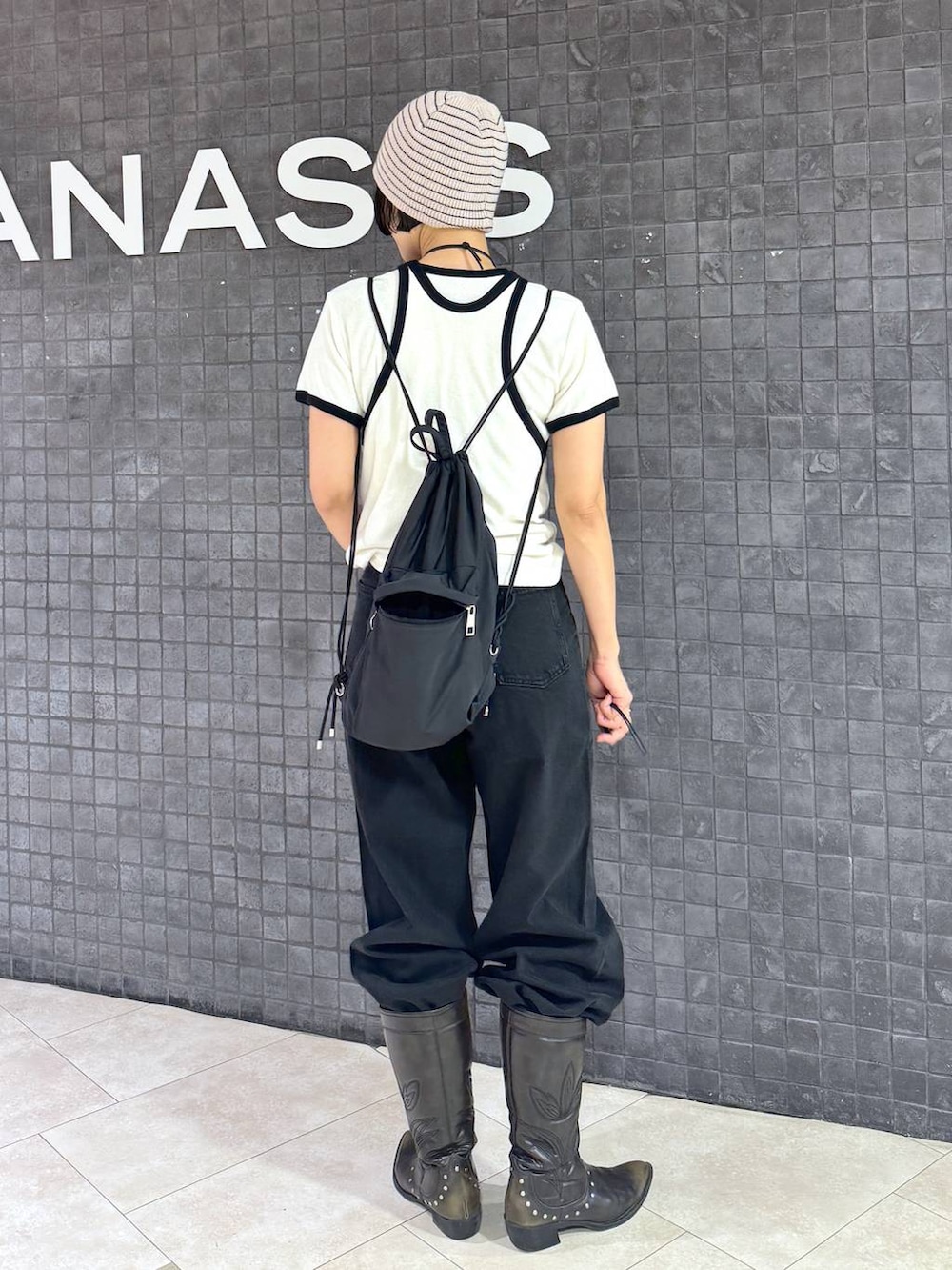 ブラック系のブーツ、ブラック系のデニムパンツ、ホワイト系のニットキャップ/ビーニーを着用したレディースの夏コーディネートの3枚目の写真