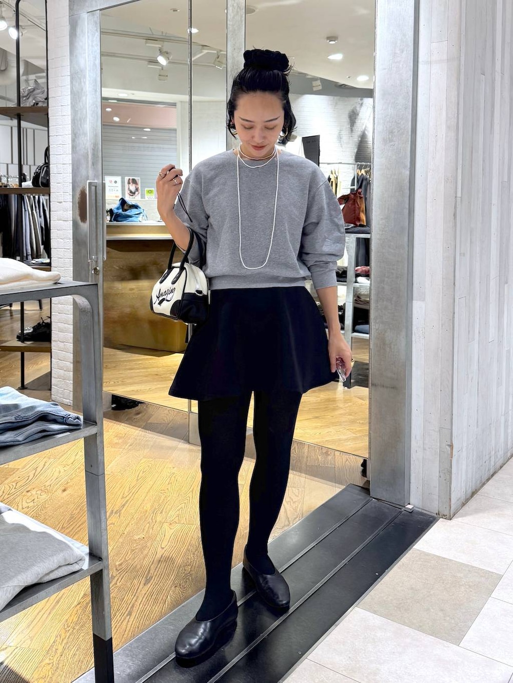 ホワイト系のショルダーバッグ、ブラック系のスカート、グレー系のスウェットを着用したレディースの秋コーディネートの3枚目の写真