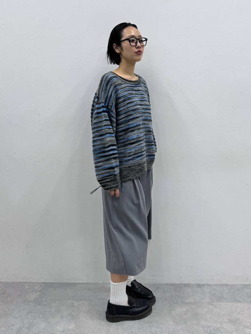 グレー系のスラックス、ブルー系のニット/セーターを着用したレディースの秋コーディネートの3枚目の写真