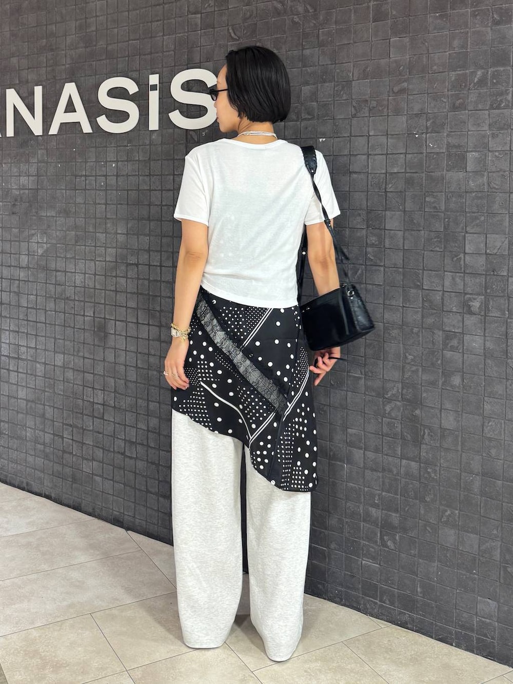 ブラック系のチュニック、ブラック系のパンプス、ホワイト系のTシャツ/カットソーを着用したレディースの夏コーディネートの4枚目の写真