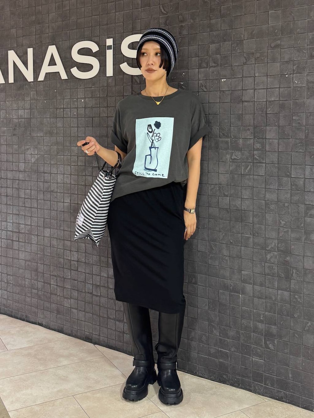 ブラック系のスカート、グレー系のTシャツ/カットソー、ブラック系のブーツを着用したレディースの夏コーディネートの3枚目の写真