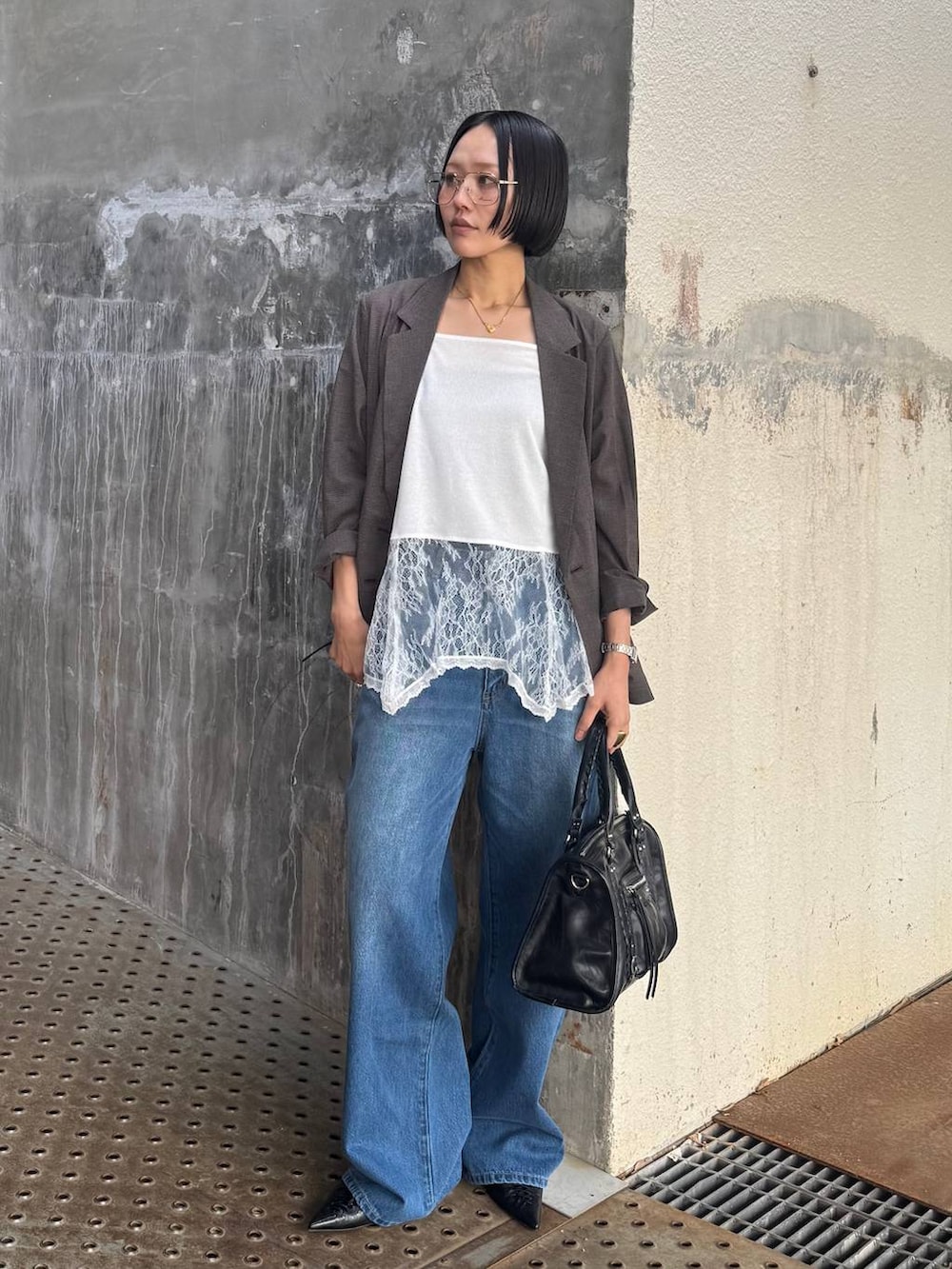 ブラック系のボストンバッグ、ブルー系のデニムパンツ、ブラウン系のテーラードジャケットを着用したレディースの春コーディネートの3枚目の写真