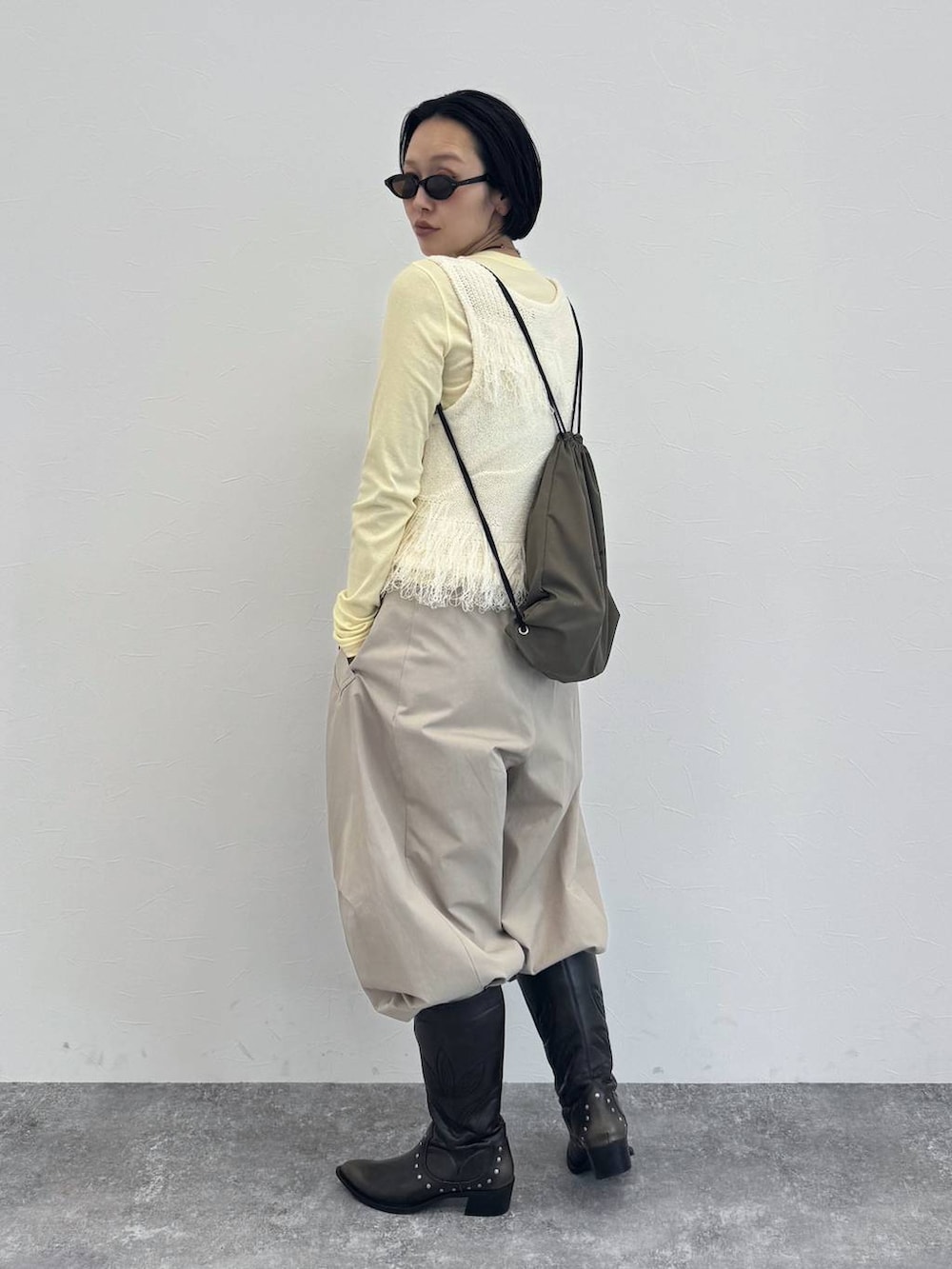 ブラック系のブーツ、イエロー系のTシャツ/カットソー、ベージュ系のその他パンツを着用したレディースの冬コーディネートの3枚目の写真