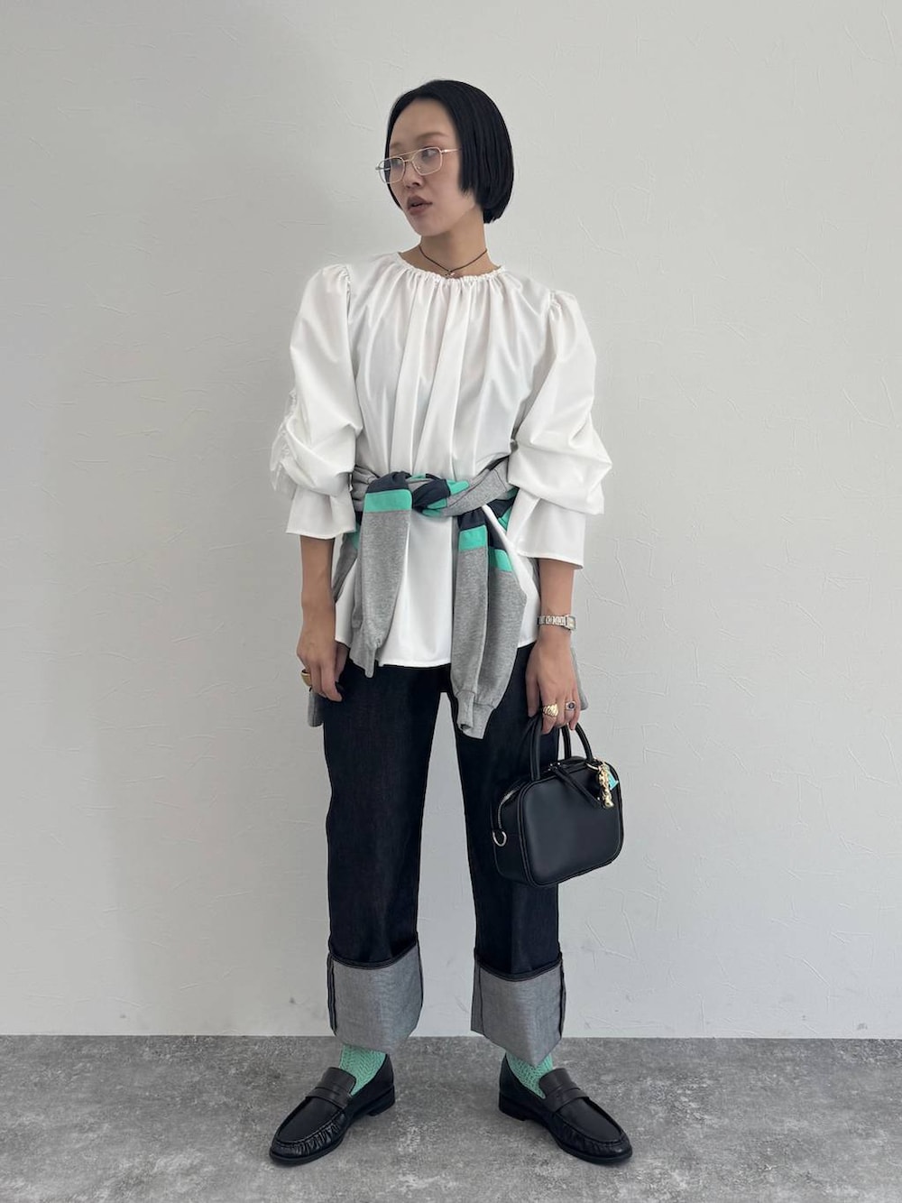 ブラック系のショルダーバッグ、ブルー系のデニムパンツを着用したレディースの冬コーディネートの2枚目の写真