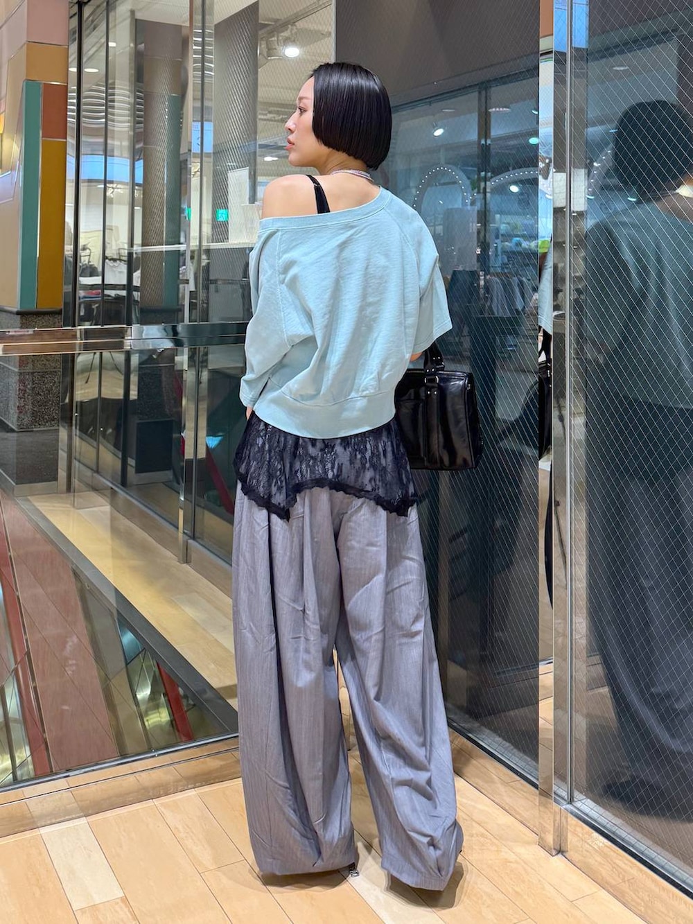 ブラック系のパンプス、ブラック系のボストンバッグ、グレー系のスラックスを着用したレディースの春コーディネートの3枚目の写真