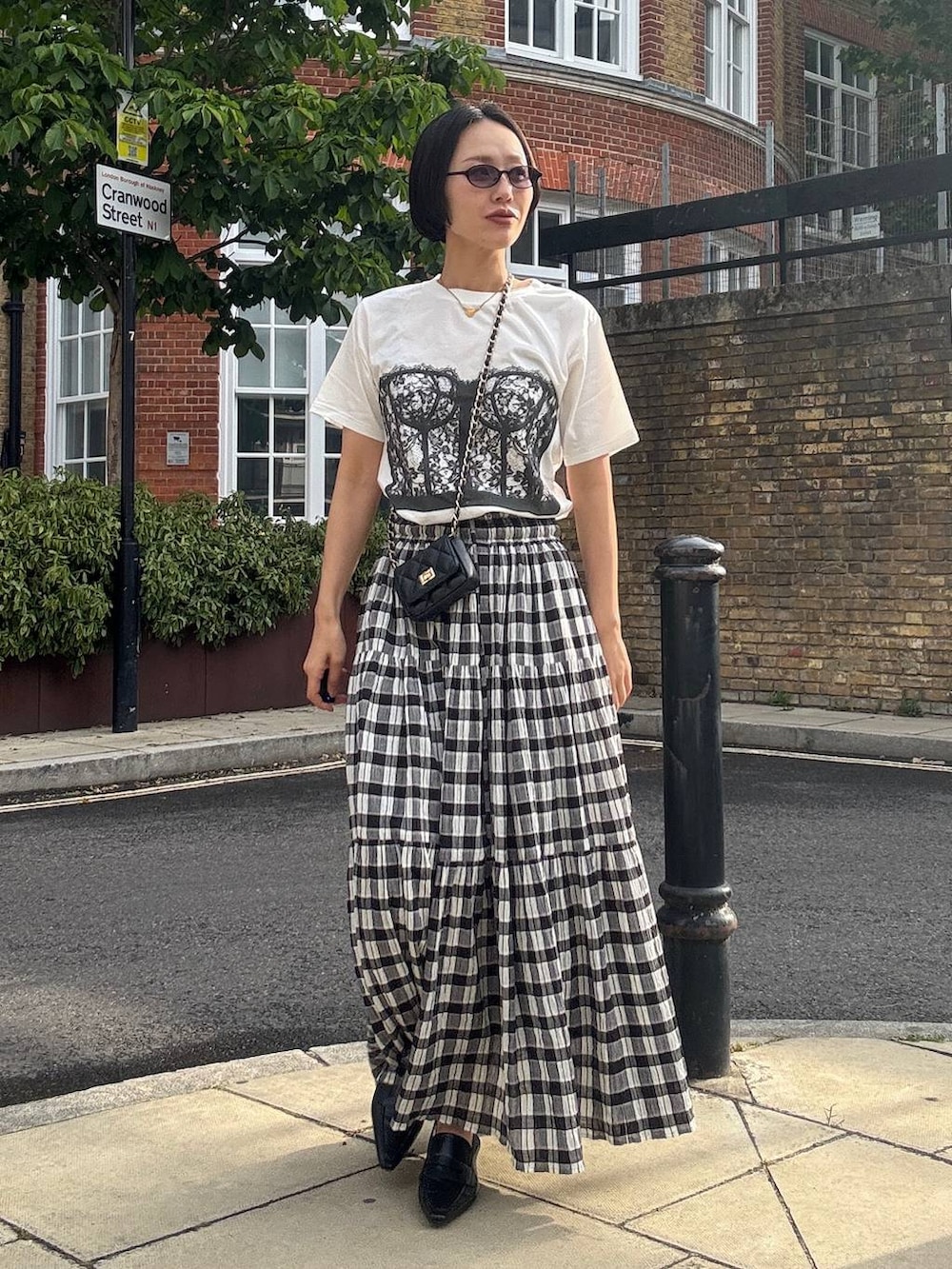 ブラック系のスカート、ホワイト系のTシャツ/カットソー、ブラック系のサングラスを着用したレディースの夏コーディネートの2枚目の写真