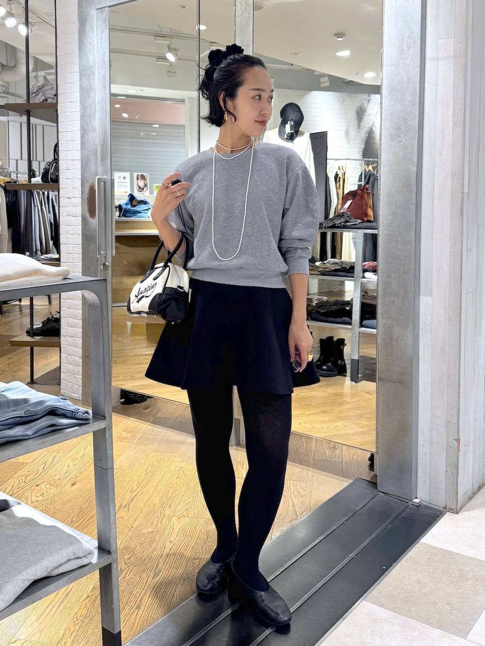 ホワイト系のショルダーバッグ、ブラック系のスカート、グレー系のスウェットを着用したレディースの秋コーディネートの2枚目の写真