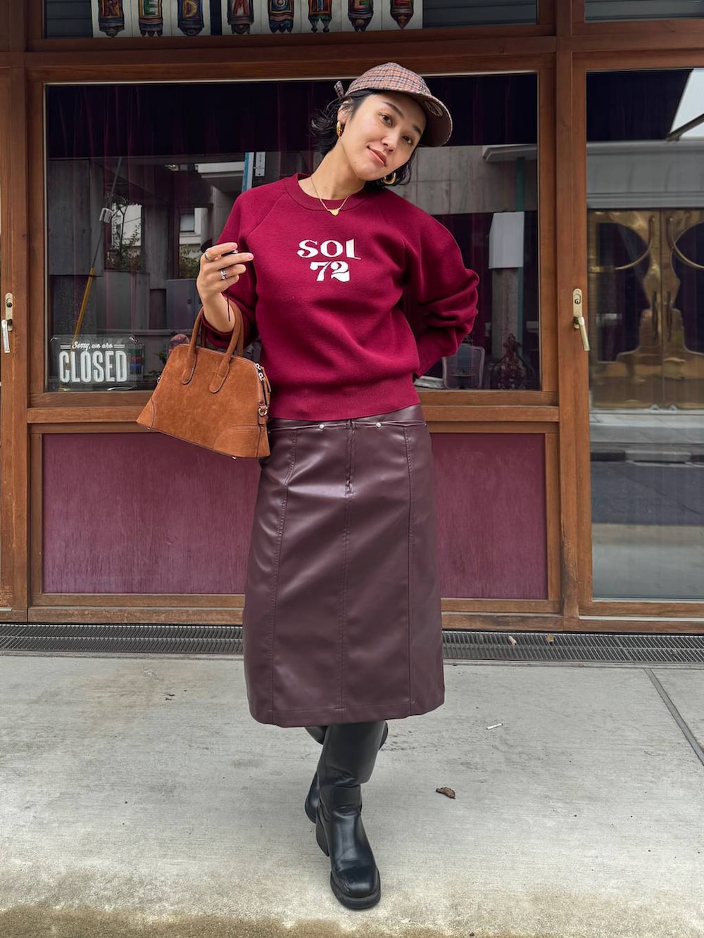 ブラウン系のボストンバッグ、ブラウン系のスカート、レッド系のニット/セーターを着用したレディースの秋コーディネートの5枚目の写真
