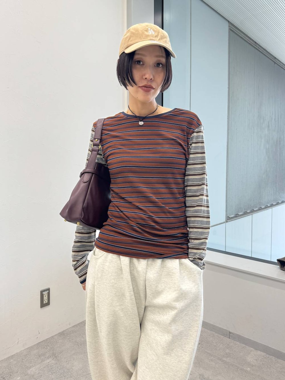 レッド系のショルダーバッグ、ホワイト系のブーツ、ベージュ系のスウェットパンツを着用したレディースの夏コーディネートの2枚目の写真