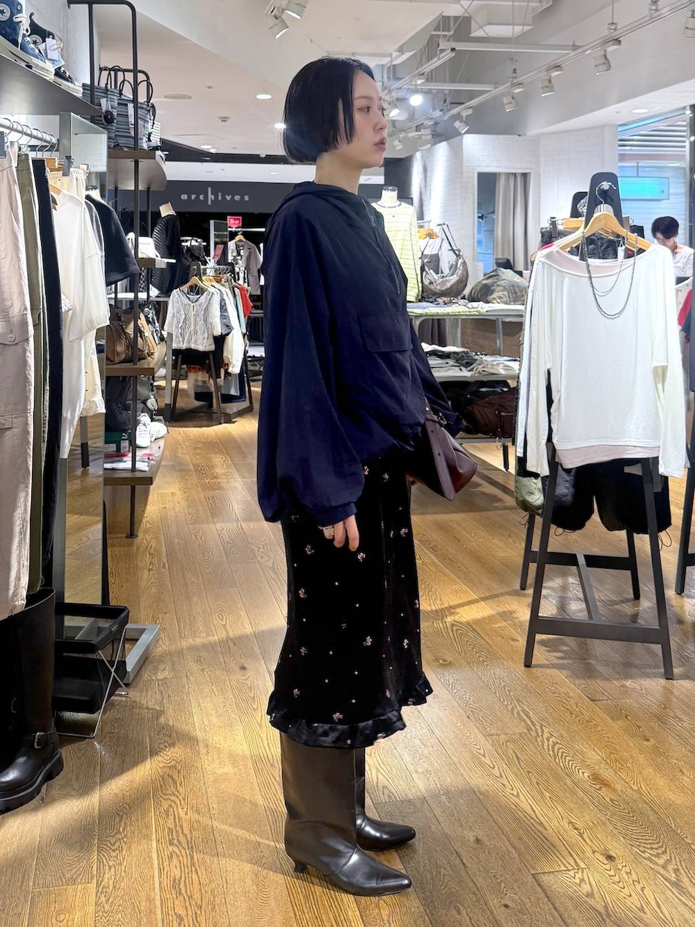 ブラック系のブーツ、ブラック系のスカート、レッド系のショルダーバッグを着用したレディースの夏コーディネートの2枚目の写真