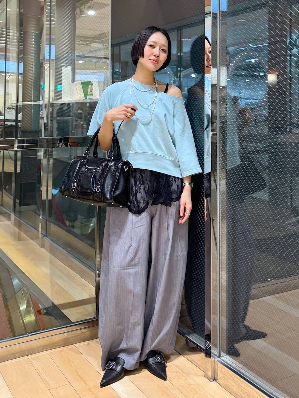 ブラック系のパンプス、ブラック系のボストンバッグ、グレー系のスラックスを着用したレディースの春コーディネートの5枚目の写真