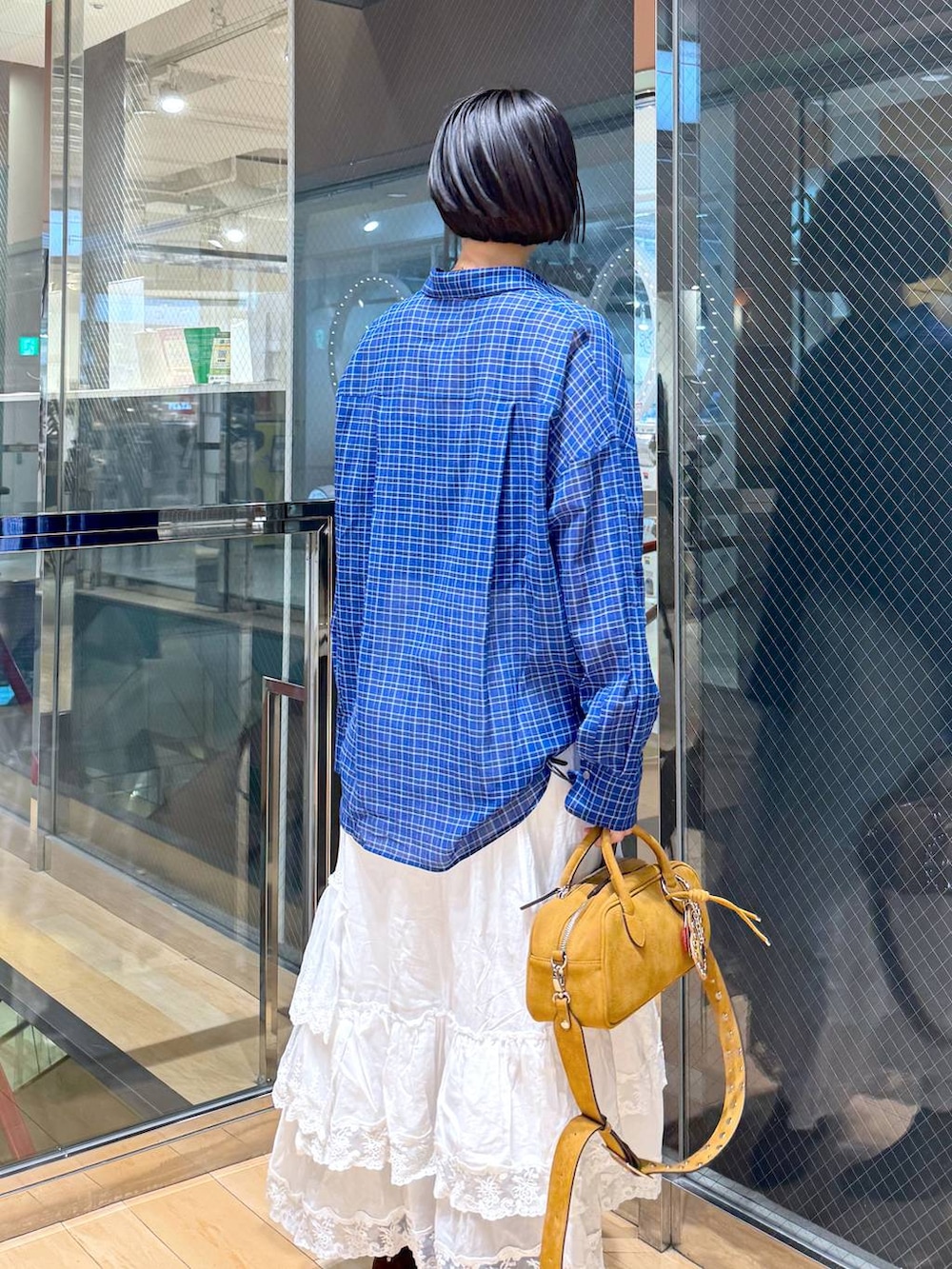 ブラウン系のボストンバッグ、ブラウン系のブーツ、ホワイト系のスカートを着用したレディースの春コーディネートの2枚目の写真