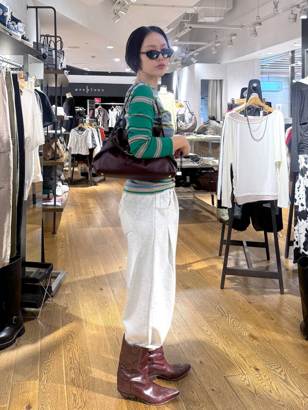 レッド系のショルダーバッグ、ベージュ系のスウェットパンツを着用したレディースの夏コーディネートの2枚目の写真