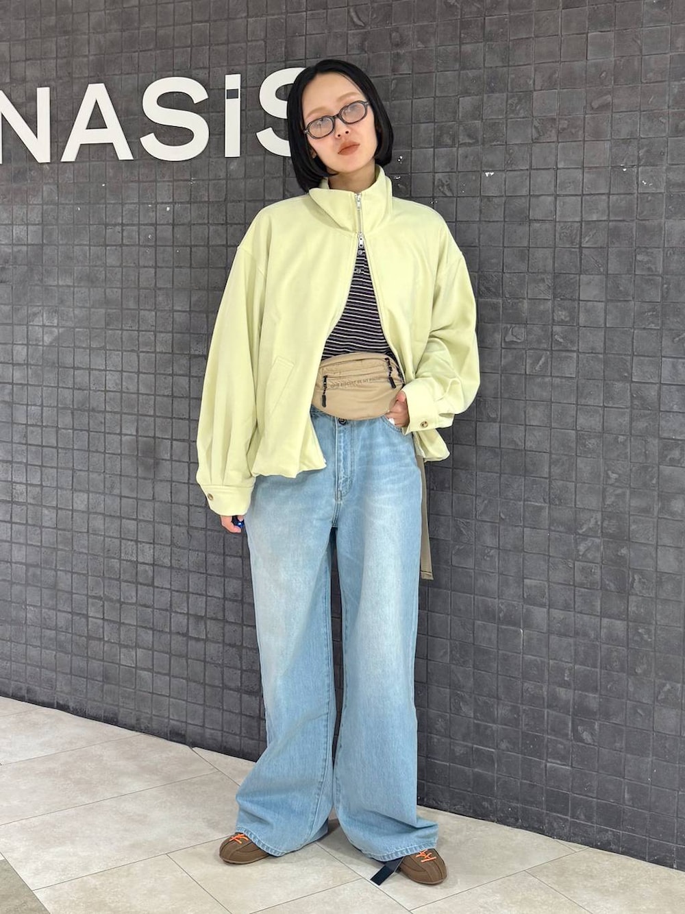 ブラウン系のTシャツ/カットソー、ブラウン系のスニーカー、ブルー系のデニムパンツを着用したレディースの春コーディネートの3枚目の写真