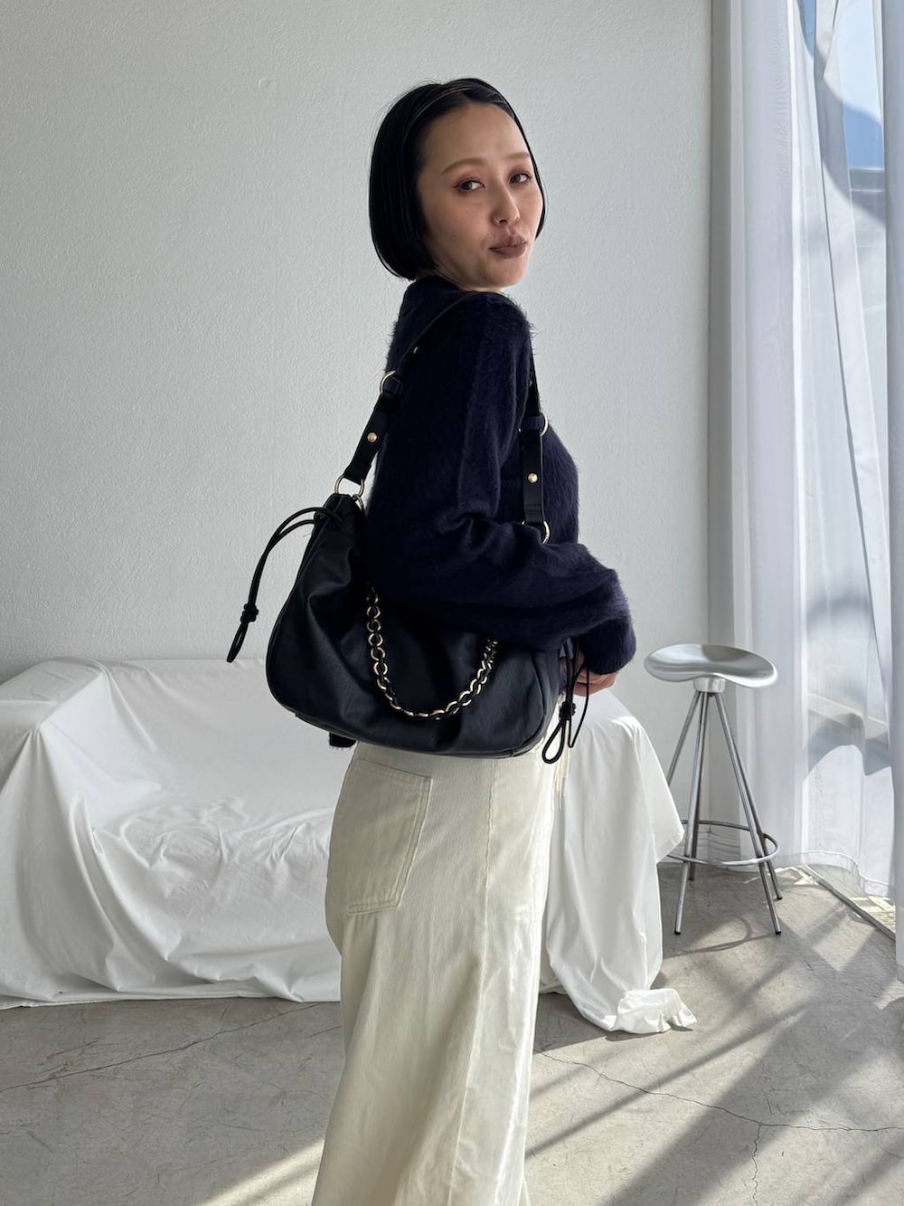 ブラック系のショルダーバッグ、ホワイト系のその他パンツ、ブルー系のカーディガン/ボレロを着用したレディースの秋コーディネートの4枚目の写真