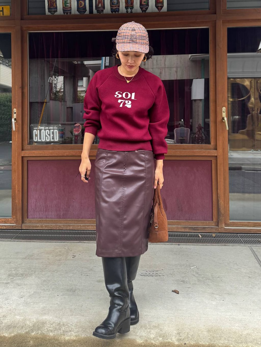 ブラウン系のボストンバッグ、ブラウン系のスカート、レッド系のニット/セーターを着用したレディースの秋コーディネートの6枚目の写真