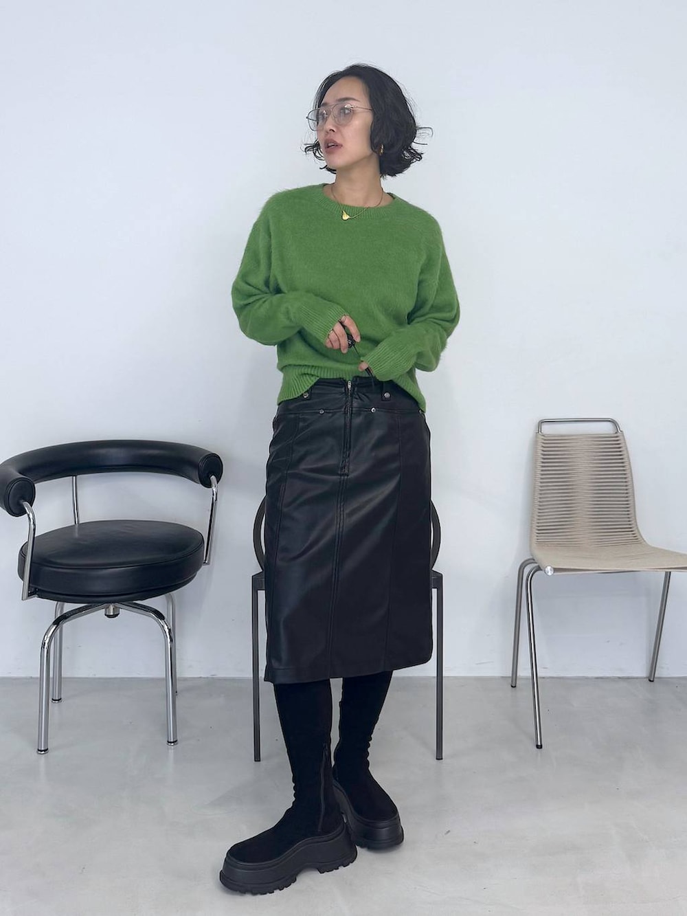 ブラック系のブーツ、グリーン系のニット/セーター、ブラック系のスカートを着用したレディースの秋コーディネートの6枚目の写真