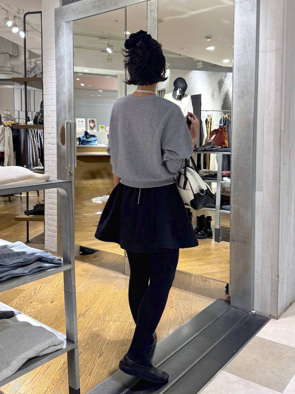 ホワイト系のショルダーバッグ、ブラック系のスカート、グレー系のスウェットを着用したレディースの秋コーディネートの5枚目の写真