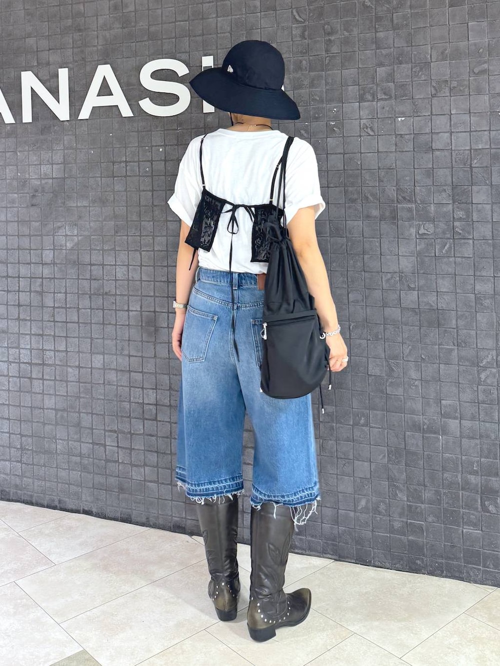 ホワイト系のTシャツ/カットソー、ブラック系のブーツ、ブルー系のデニムパンツを着用したレディースの夏コーディネートの2枚目の写真