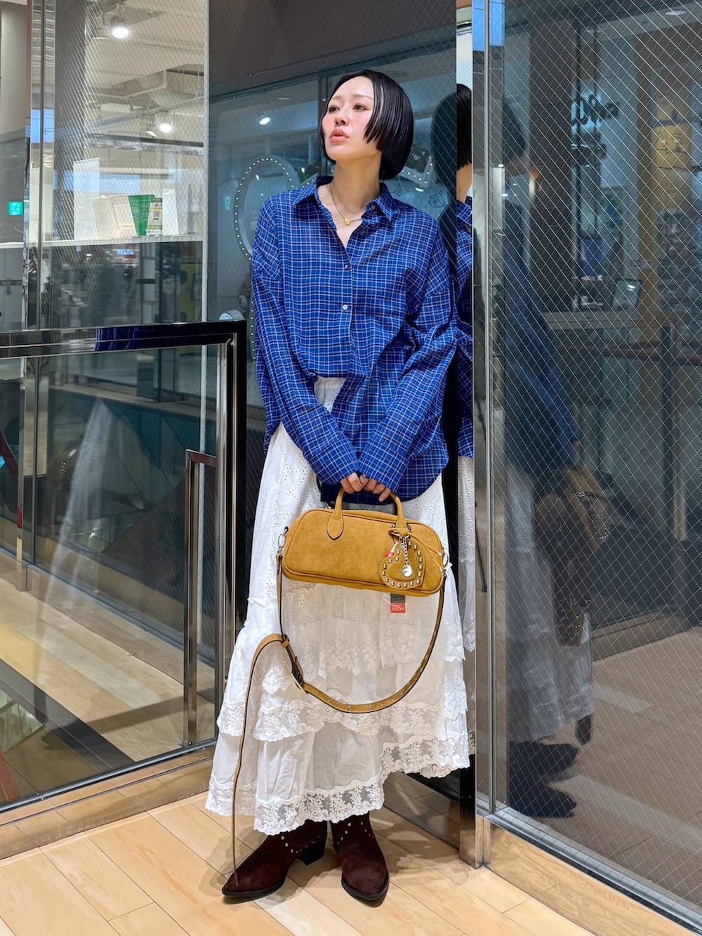 ブラウン系のボストンバッグ、ブラウン系のブーツ、ホワイト系のスカートを着用したレディースの春コーディネートの5枚目の写真