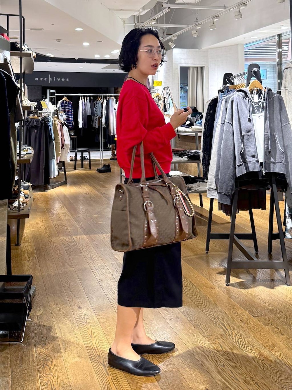 グリーン系のトートバッグ、ブラック系のその他パンツ、レッド系のスウェットを着用したレディースの秋コーディネートの4枚目の写真