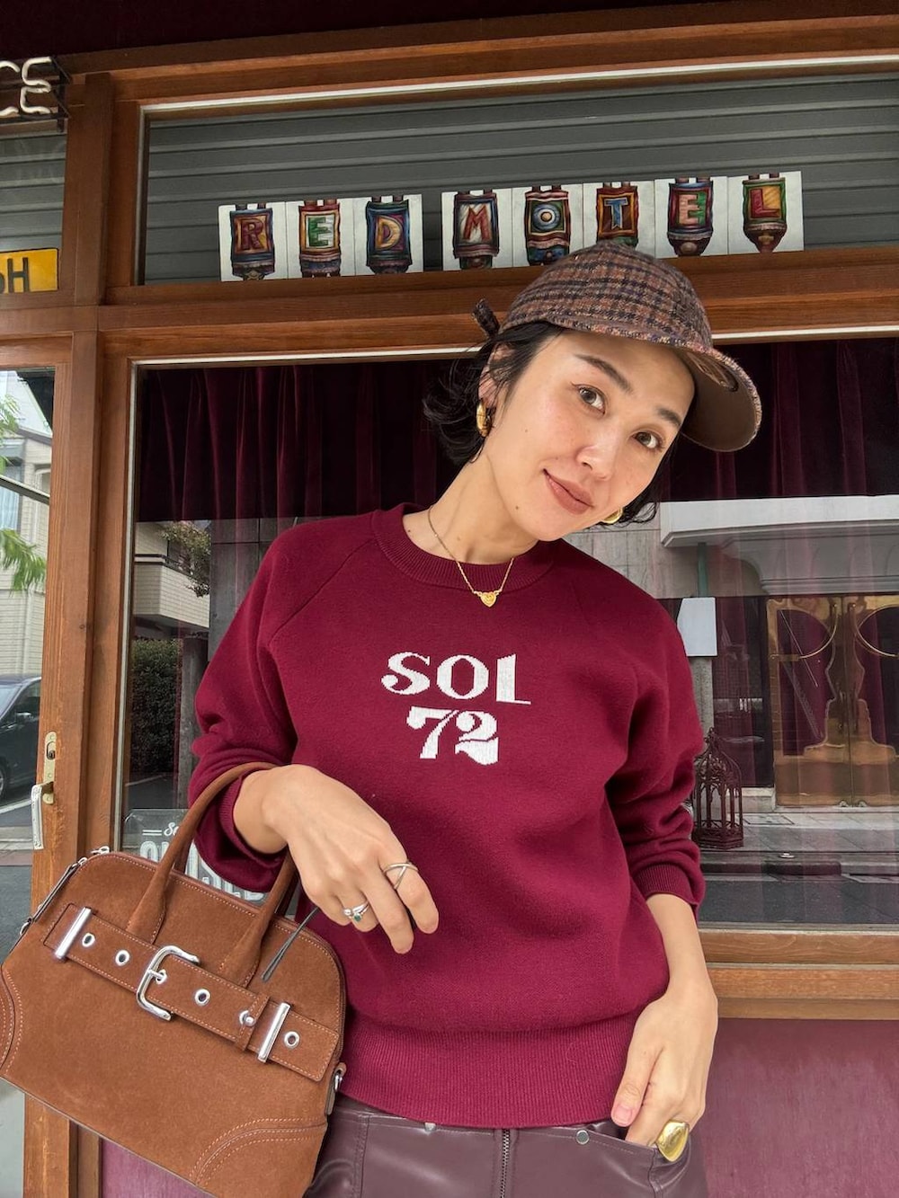 ブラウン系のボストンバッグ、ブラウン系のスカート、レッド系のニット/セーターを着用したレディースの秋コーディネートの3枚目の写真