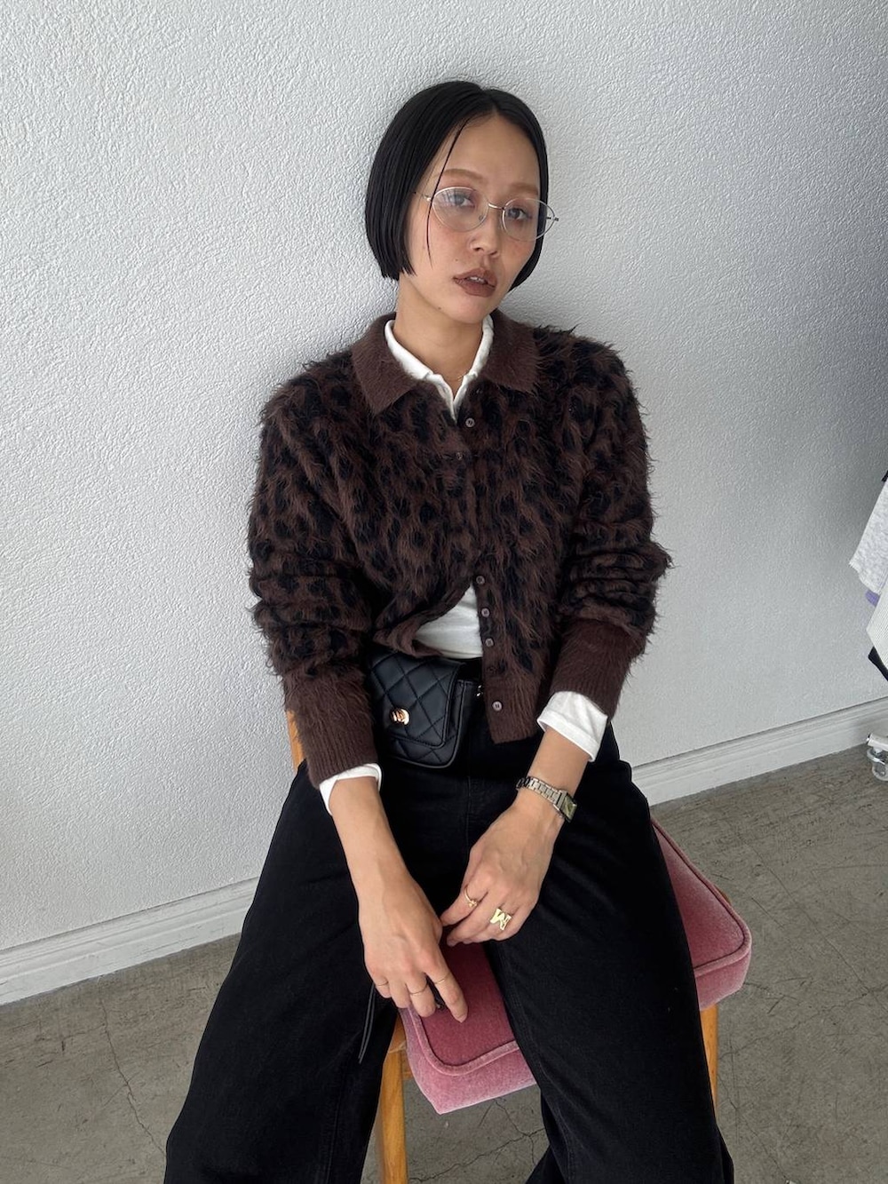 ブラック系のデニムパンツ、ホワイト系のポロシャツ、ブラウン系のカーディガン/ボレロを着用したレディースの秋コーディネートの3枚目の写真